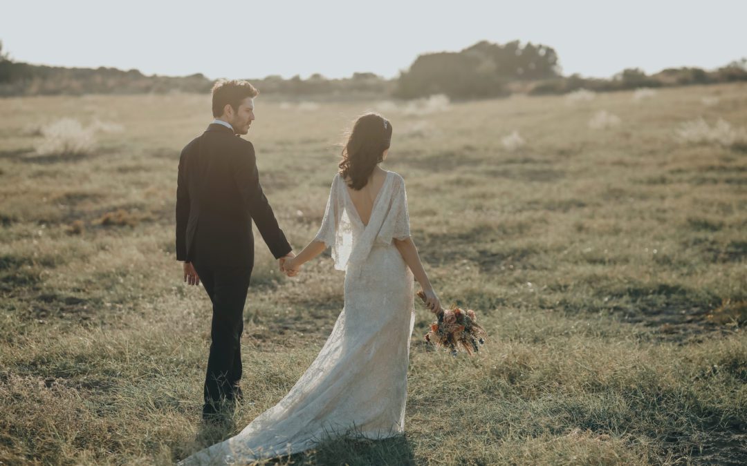 Bride and groom after wedding walking and taking photographs in field