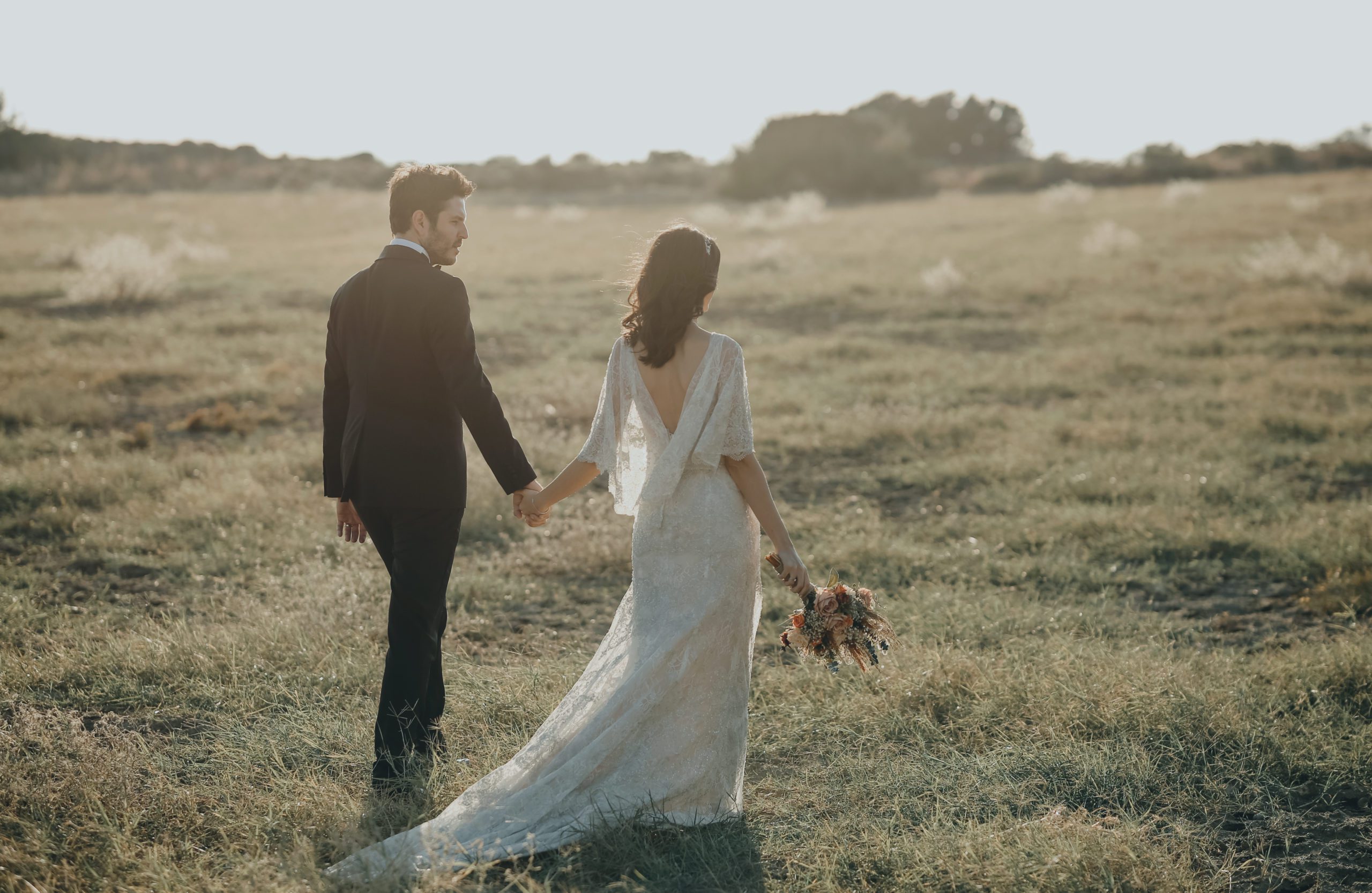 Bride and groom after wedding walking and taking photographs in field