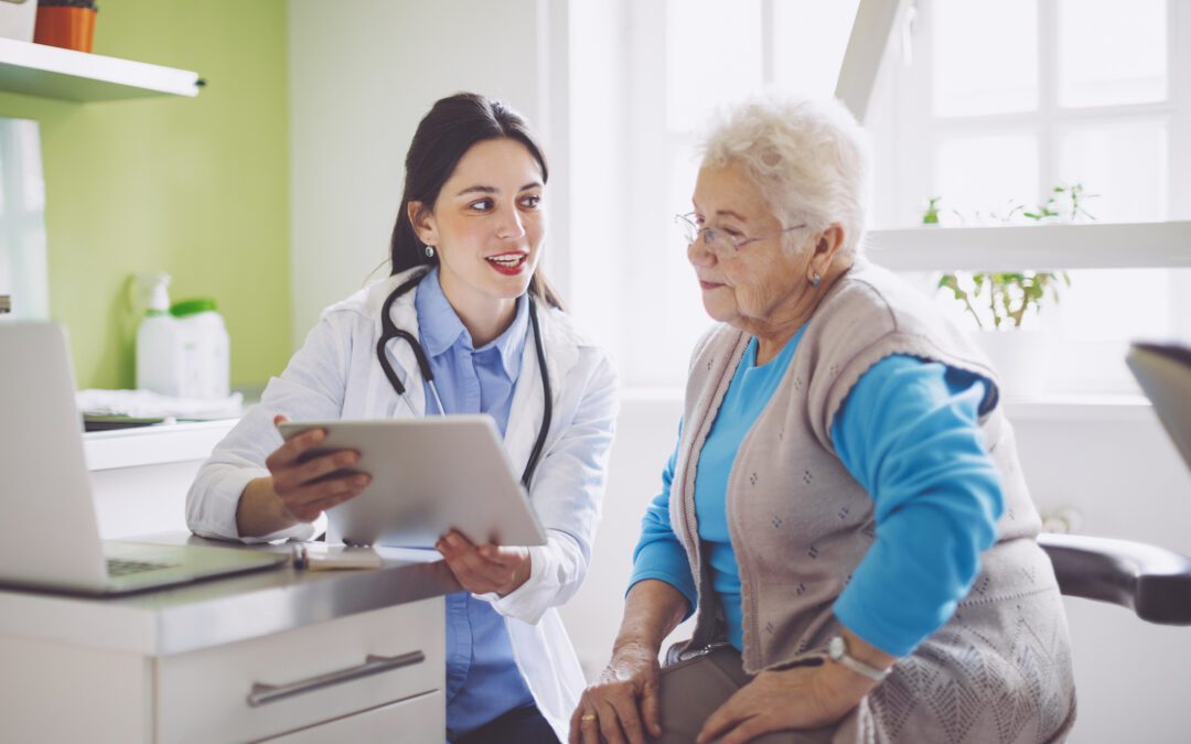 Older patient at doctor's office with doctor reviewing results on a tablet