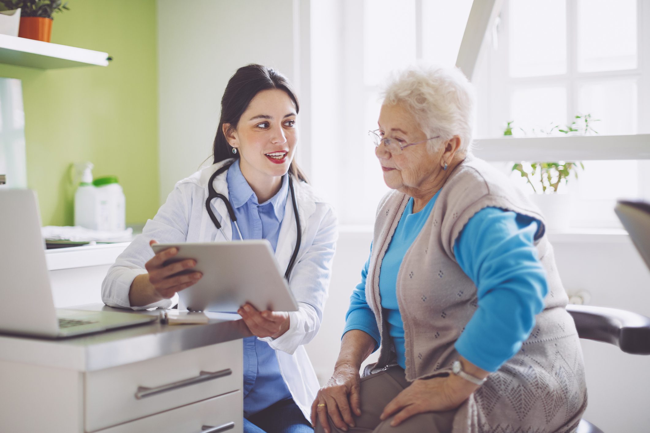 Older patient at doctor's office with doctor reviewing results on a tablet