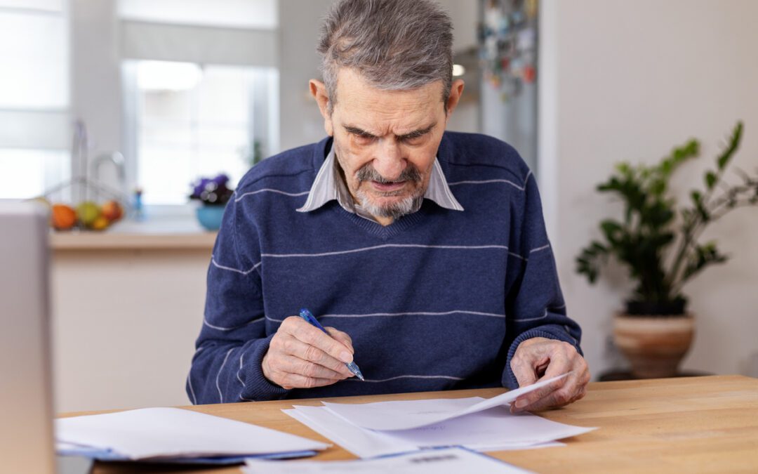 Senior man reviewing documents, potentially social security benefit documentation, with frustration