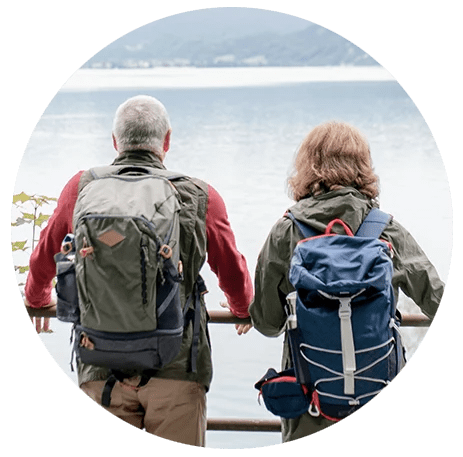 wealth management image of elderly couple with hiking backpacks looking out on lake from godsey and gibb