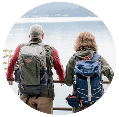 Retired couple with backpacks overlooking water and mountains representing greenville sc wealth management clients