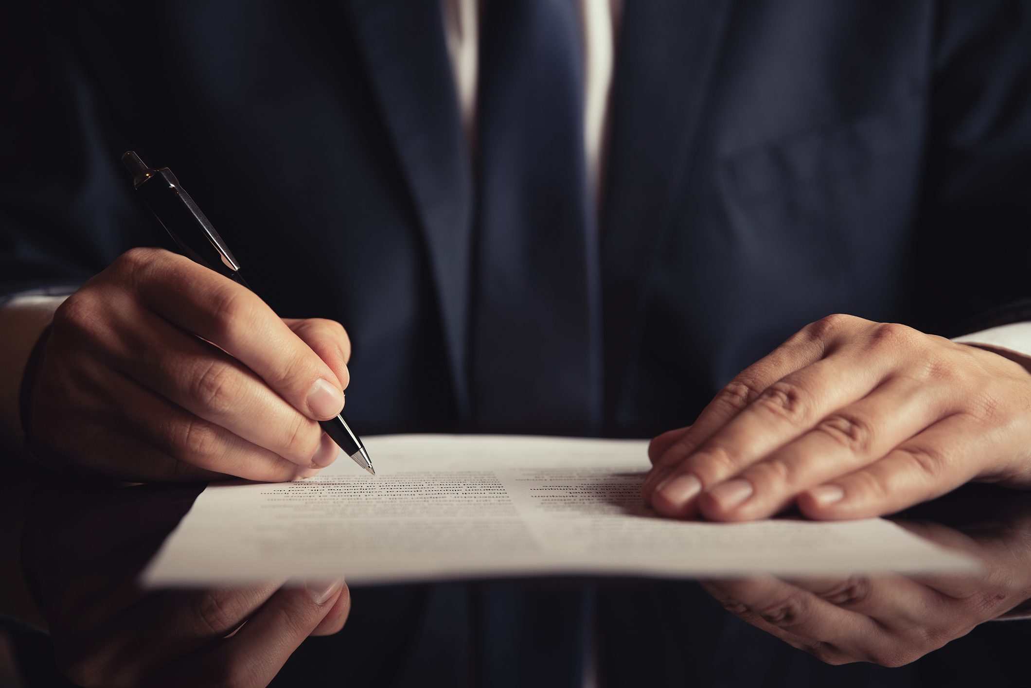 Man in suit signing legal document representing a revocable trust or irrevocable trust