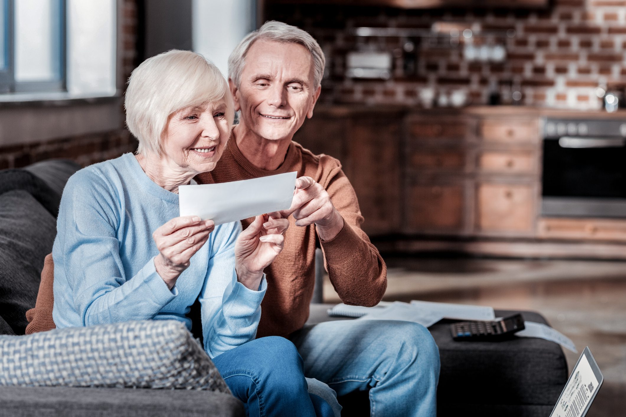 Delighted senior people being happy together Good for you. Smiling male person embracing his wife while pointing at counting