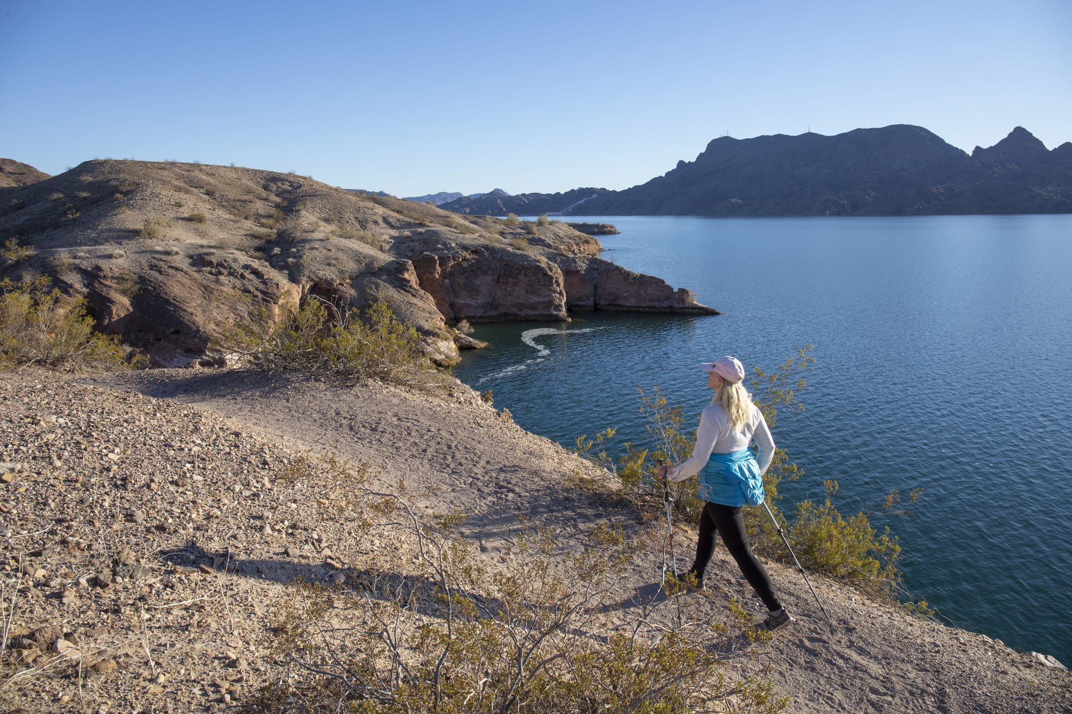 Woman hikes along sunny mountain ridge