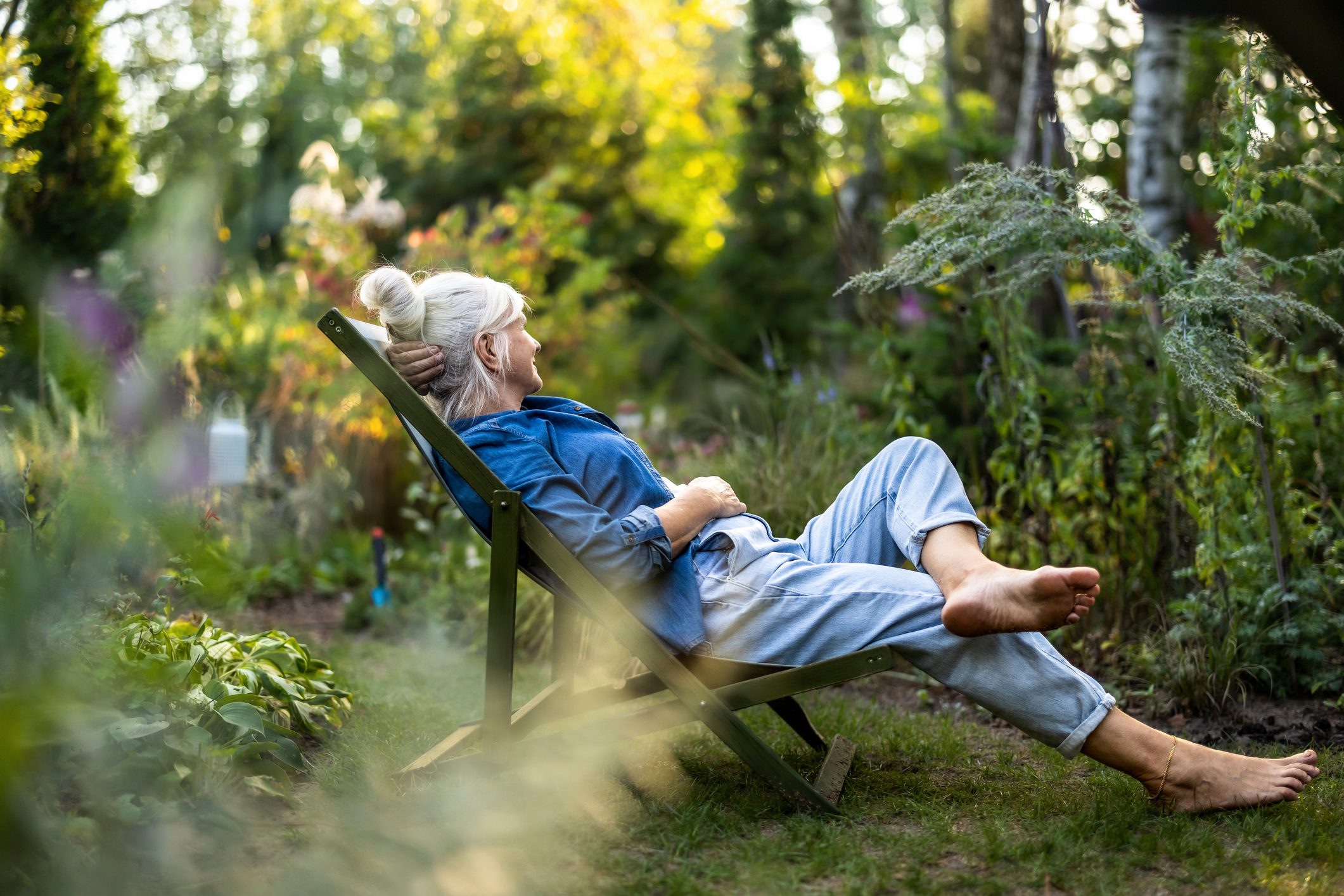 Mature woman relaxing in deckchair in her garden Mature woman relaxing in deckchair in her garden