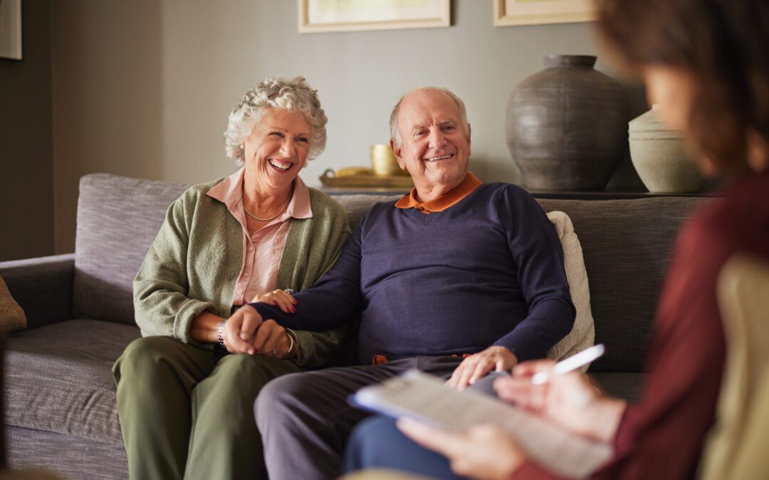 Elderly patients engaging with medical practitioner for health advice and insurance guidance. Senior couple attentively listening to a psychologist woman during consultation at home. Caring female social worker explaining health matters to an elderly couple at home.