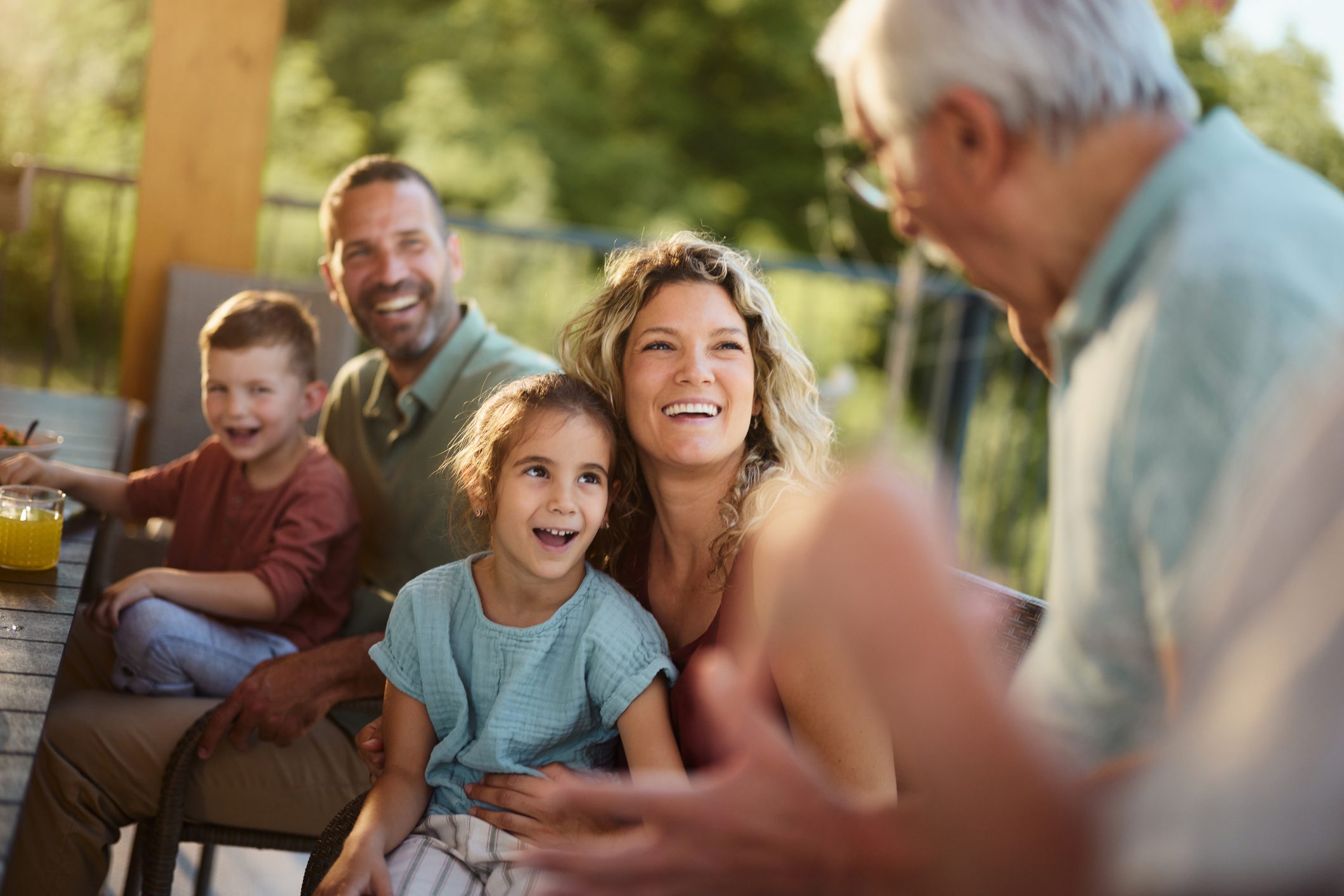 Happy family communicating with senior grandfather on a patio.