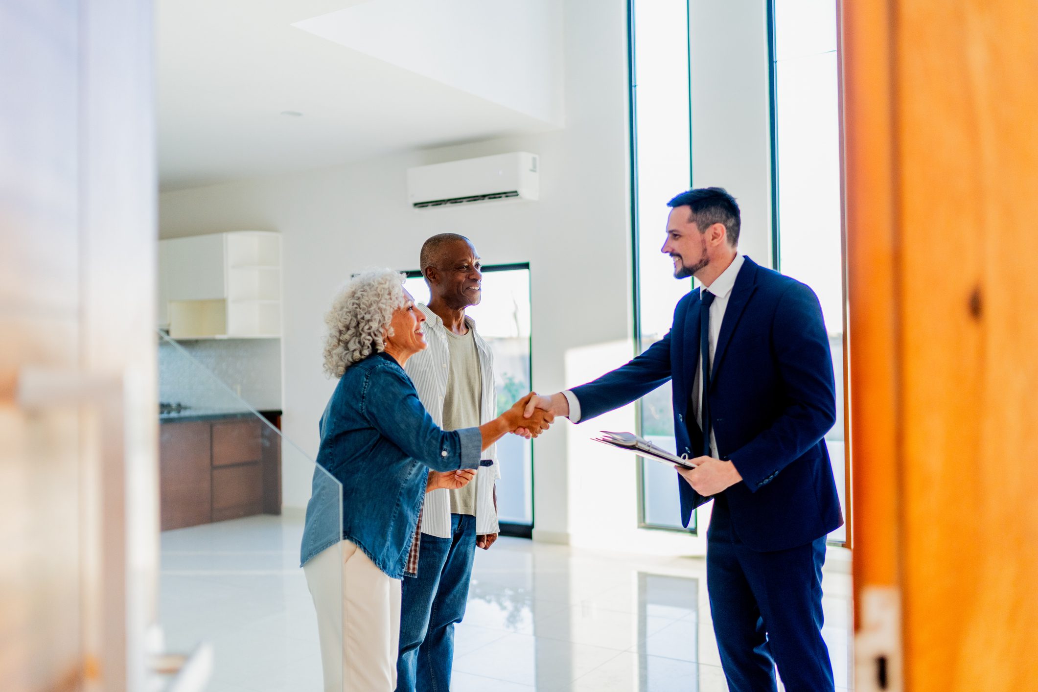 Senior couple closing deal with real estate agent at house